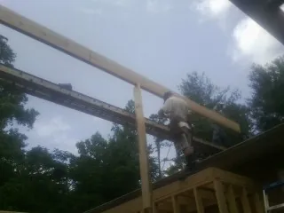 Carpenter setting a ridge beam over a new addition frame — Ice Dam Removal by Roofing Brothers in Crookston