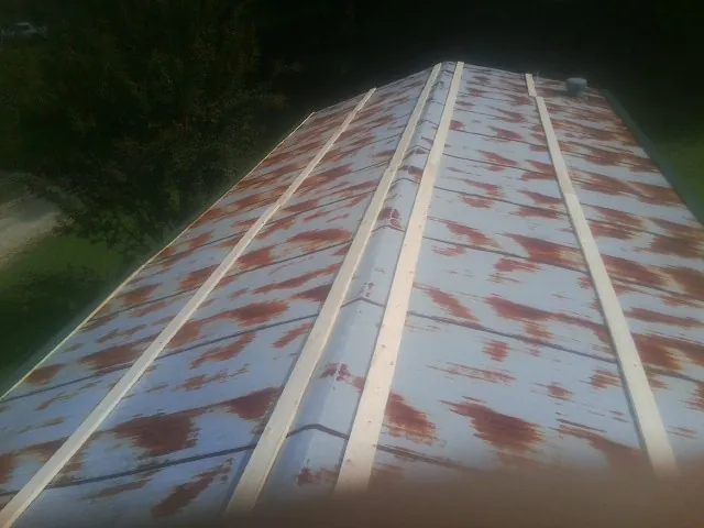Rusted metal roof panels with new wood purlins before replacement — Storm Damage Roof Repair in Crookston by Roofing Brothers