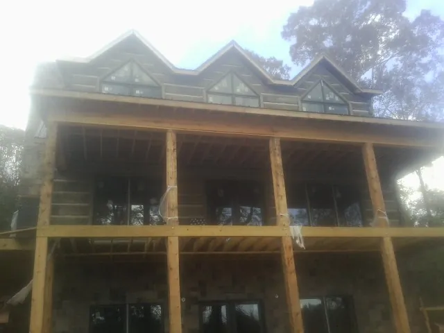 Dormers and porch framing on a large log home under construction — Roof Coating work by our crew in Crookston