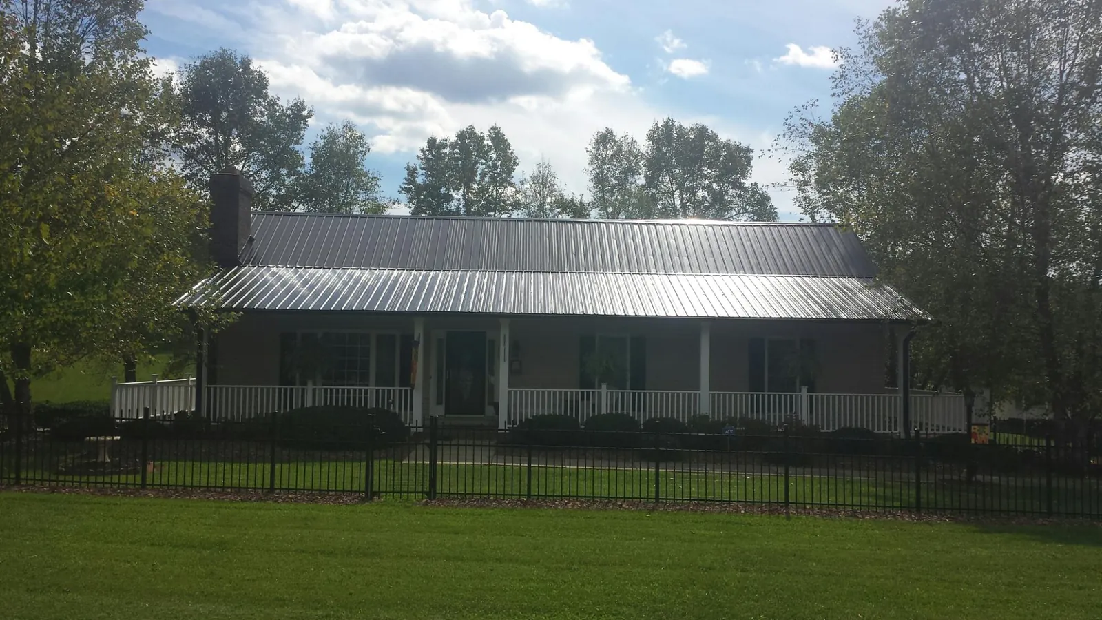 Gray metal roof on a brick ranch with a full width front porch — Gutter Guard Installation work by our crew in Crookston