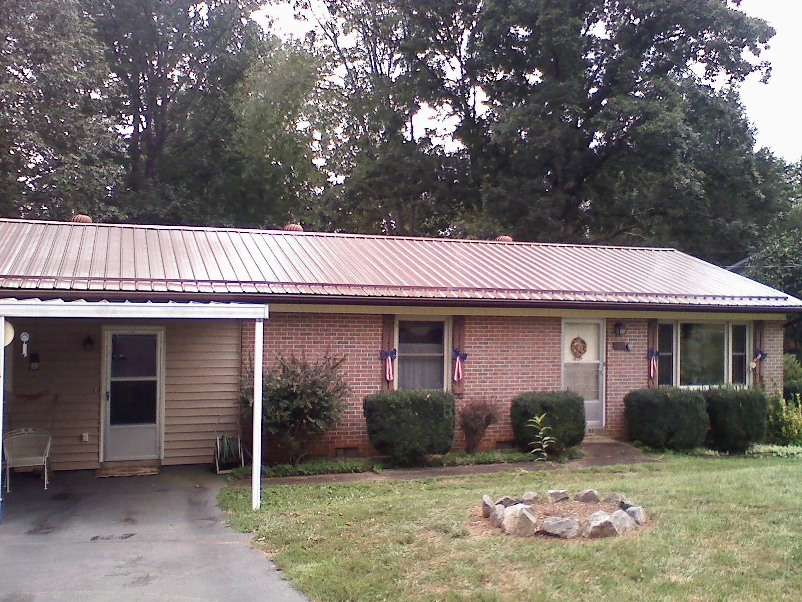 Bronze metal roof and carport on a brick ranch home — Roof Repair work by our crew in Crookston