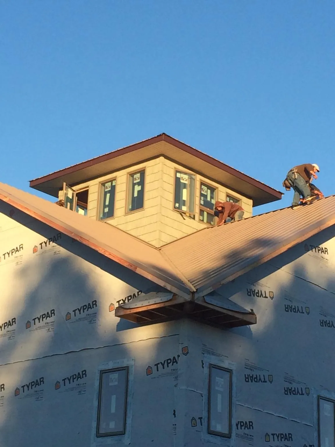 Roofers working around a rooftop cupola on a new metal roof at sunset — Roof Waterproofing in Crookston by Roofing Brothers